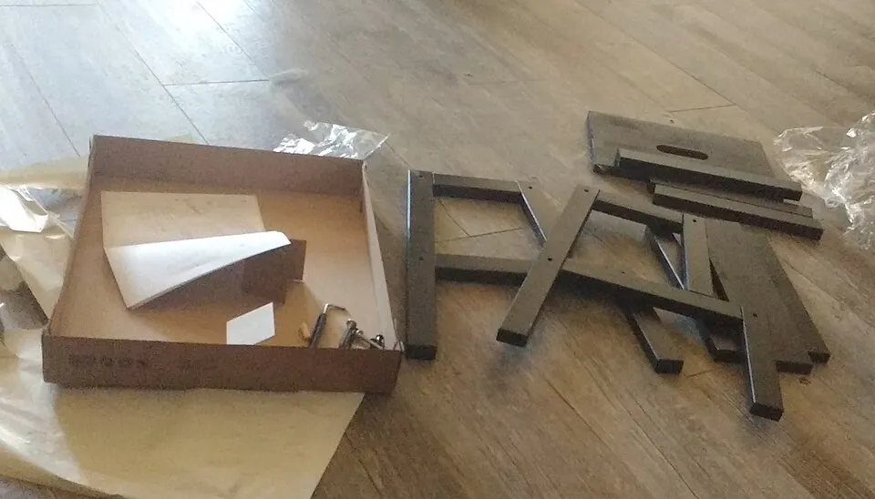 Các tấm ván và phụ kiện của tủ lắp ráp được bày ra sàn.